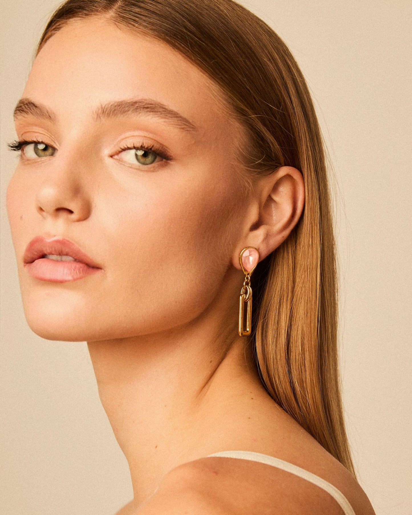 Modelo luciendo pendientes en forma de gota bañados en oro de 24k con cristal Swarovski® en forma de lágrima y colgante rectangular.