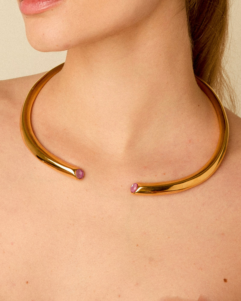 Model wearing a 24K gold plated open collar necklace with fuchsia Swarovski crystals around her neck, highlighting its elegant fit, unique open design, and how it drapes on the skin.