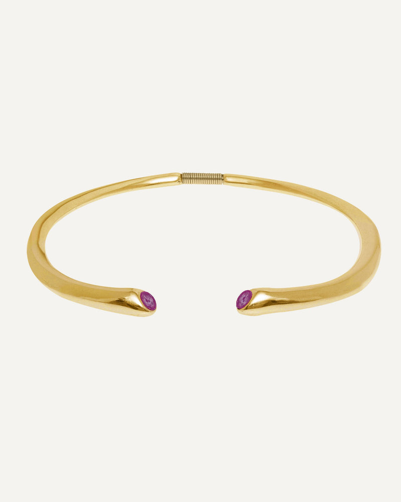 Close-up of a 24K gold plated open collar necklace with two fuchsia Swarovski crystals on a clean studio background, showcasing its curved design and details.