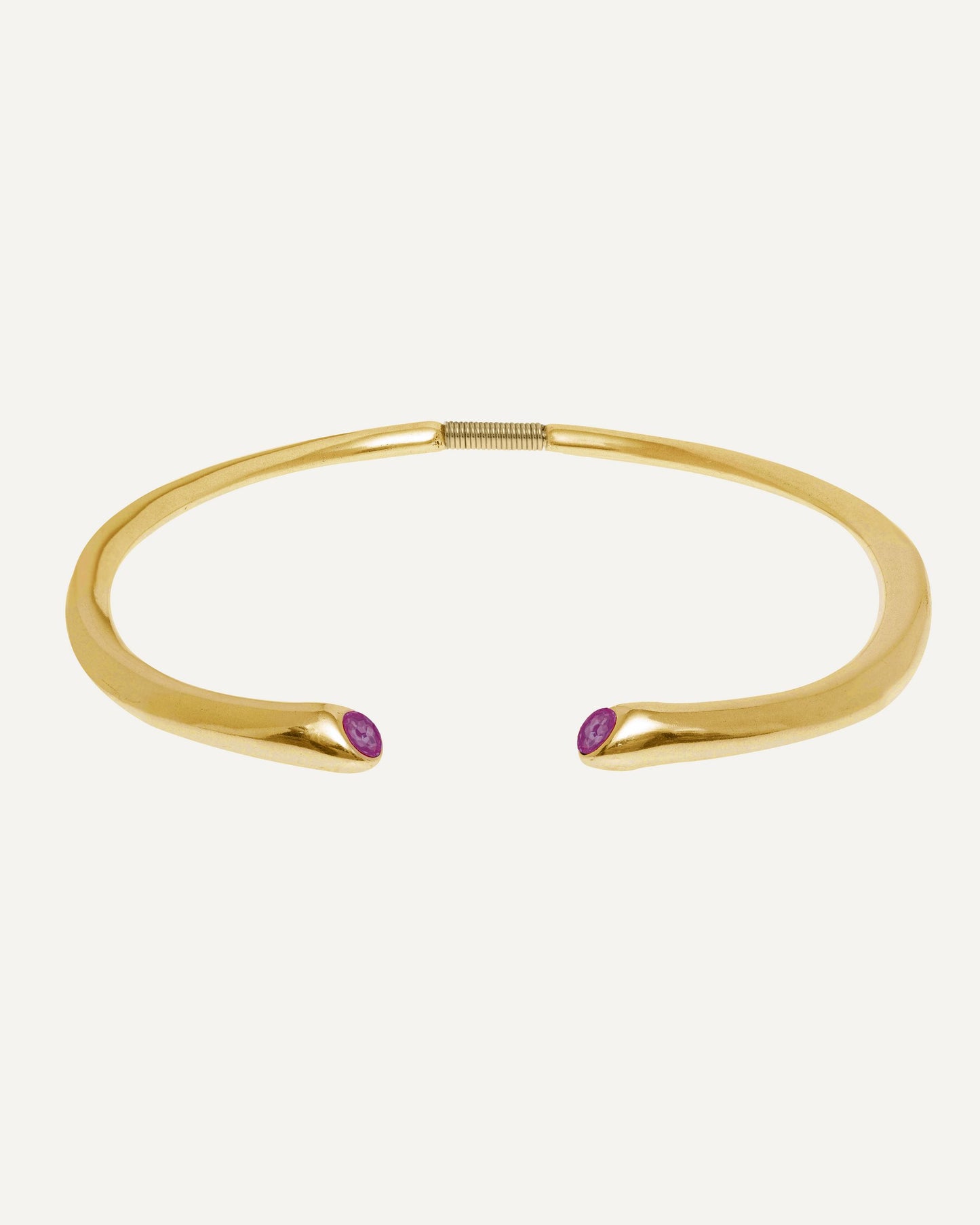 Close-up of a 24K gold plated open collar necklace with two fuchsia Swarovski crystals on a clean studio background, showcasing its curved design and details.