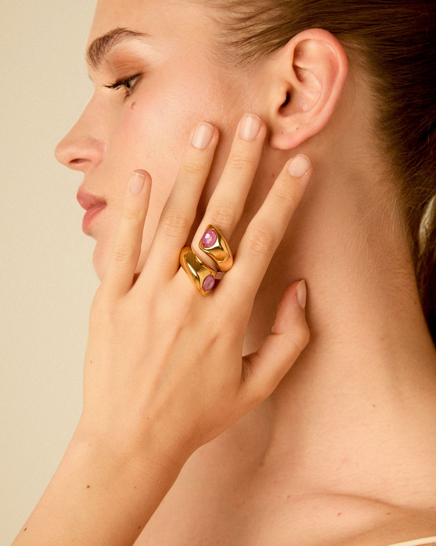 Model wearing a chunky 24K gold plated open ring with fuchsia Swarovski crystals on her finger, highlighting the ring's scale, fit, and elegant style on skin.